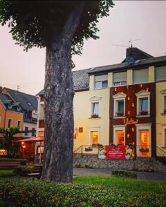 ein großes Gebäude mit einem Baum davor in der Unterkunft Hotel Restaurant Unikat in Zeltingen-Rachtig