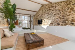 a living room with a couch and a stone wall at Suites D´aldeia - Suite 16 in Mafra