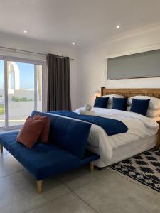 Santorini Guesthouse في امانزيمتوتي: غرفة نوم بسرير كبير وأريكة زرقاء