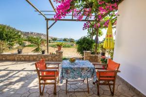 a patio with a table and chairs and a umbrella at Venetia's Garden in Lefkos Karpathou