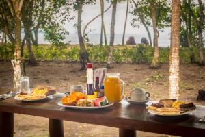 a wooden table with plates of food and orange juice at Playa Ganadito Ecolodge in Drake