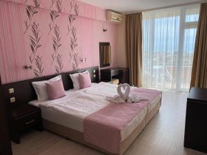 a bedroom with a large bed with a pink wall at Hotel Ancora Beach in Primorsko