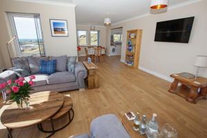 a living room with a couch and a table at Sea Spray Cottage in Pollachar