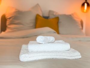 a stack of white towels on a bed at Modernes Apartment im Kaiserkiez in Oldenburg