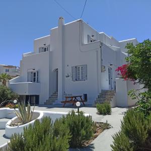 un gran edificio blanco con algunas plantas delante de él en Isalos Paros, en Naousa