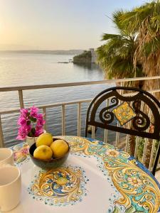 a table with a bowl of fruit on top of a balcony at Castello a Mare in Castellammare del Golfo