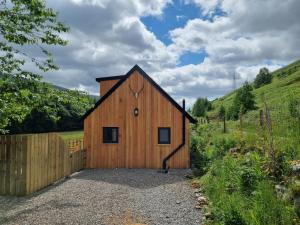 a wooden barn with a fence in a field at Cozy Nook in Spean Bridge