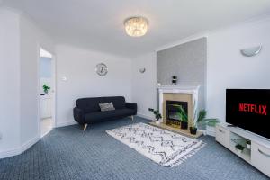 a living room with a black couch and a fireplace at Family friendly 3-bed home with free parking on site in Lindley