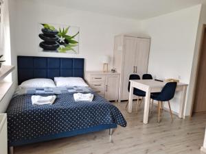 a bedroom with a blue bed and a table and chairs at Domki i Pokoje Baltimor in Grzybowo