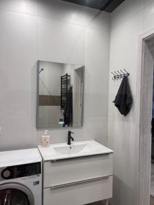 a white bathroom with a sink and a washing machine at Przytulna kawalerka w kamienicy in Ełk