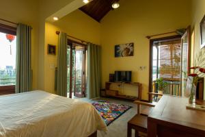 Schlafzimmer mit gelben Wänden, einem Bett und Fenstern in der Unterkunft Chez Xuan - Private Villa Hoian in Hoi An