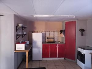 a kitchen with a white refrigerator and red cabinets at Our Place - Family - 5 bed unit in Bloemfontein