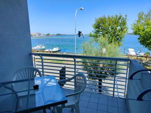 balcón con mesa, sillas y vistas al agua en Hotel Capri en Grado