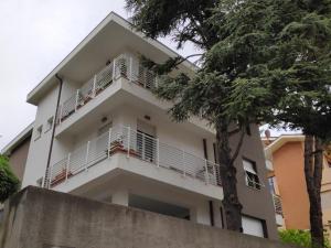 a white house with a tree in front of it at Appartamento Panoramica in Pesaro