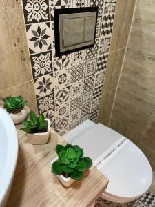 ein Badezimmer mit WC und Topfpflanzen auf einem Tisch in der Unterkunft Diamond Luxury Apartment Near Presidential Palace in Bukarest