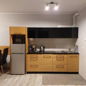 eine Küche mit einem weißen Kühlschrank und Holzschränken in der Unterkunft Komfortowy apartament w zachodniej części Kołobrzegu in Kołobrzeg