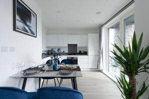 uma cozinha e sala de jantar com uma mesa e cadeiras azuis em Luxury penthouse with stunning views near Canary Wharf em Londres