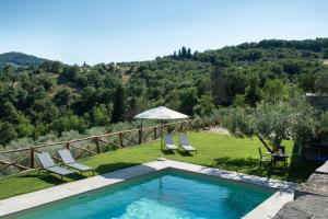 - une piscine avec 2 chaises longues et un parasol dans l'établissement Tuscan farmhouse with spectacular views, à Rufina