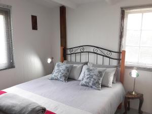 sypialnia z łóżkiem z białą pościelą i poduszkami w obiekcie Storms River Tin House w mieście Stormsrivier