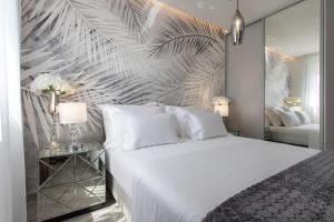 1 dormitorio con 1 cama blanca grande y papel pintado de hoja grande en Apartments Taratta 1, en Trogir