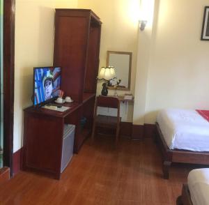 a hotel room with a bed and a desk with a television at Soutikone Place House 2 in Luang Prabang