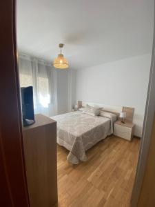 a white bedroom with a bed and a television at Apartament Acollidor a Ribes de Freser in Ribes de Freser