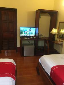 a hotel room with a television and a bed at Soutikone Place House 2 in Luang Prabang