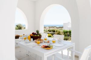 a white dining room with a white table with food on it at Pyrgaki Beach Villa in Aliko Beach