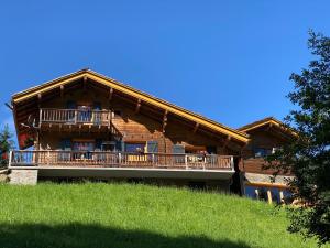 a large wooden house with a balcony on a hill at Chalet de l'Ours : 4 étoiles-spa-proche des pistes in La Clusaz