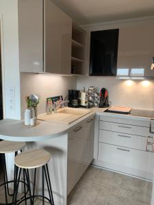 una cocina con armarios blancos y una barra con taburetes en Petit appartement cosy en Villers-sur-Mer