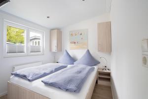 a white bedroom with blue pillows on a bed at Ostseecamp Lübecker Bucht Meeresbrise in Scharbeutz