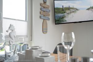 a dining room with a table with wine glasses and a tv at Ostseecamp Lübecker Bucht Meeresbrise in Scharbeutz