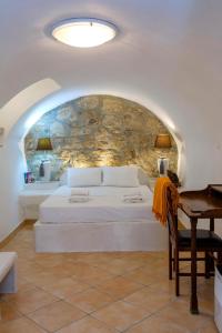 ein Schlafzimmer mit einem weißen Bett und einer Steinwand in der Unterkunft Campiello Apartments in Korfu-Stadt