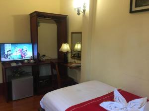 Habitación de hotel con cama y TV en Soutikone Place House 2, en Luang Prabang