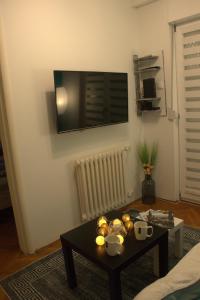 a living room with a table and a tv on the wall at Novi Sad Apartman Tenigo in Novi Sad