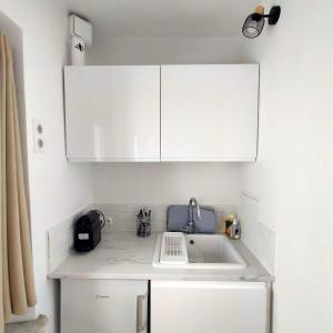 a kitchen with white cabinets and a sink at Joli studio dans le coeur de Menton in Menton