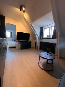 a living room with a table and a tv at Studio Wijkhuizen in Zandvoort