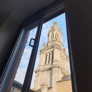 Blick auf einen Uhrturm durch ein Fenster in der Unterkunft Appartement au n°1 centre d'Avranches in Avranches