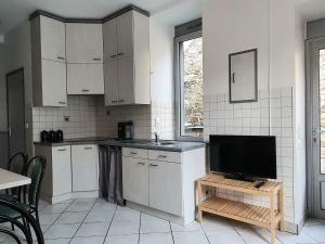 una cucina con armadi bianchi e una TV a schermo piatto di Appartement au n°1 centre d'Avranches ad Avranches
