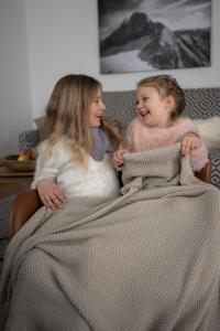 two young girls sitting in a bed under a blanket at Dependance Dachsteinperle in Ramsau am Dachstein