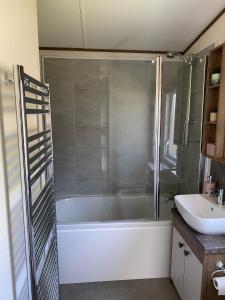 y baño con ducha, bañera y lavamanos. en Heywoods caravan holiday home en Morecambe
