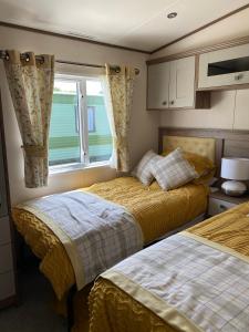 1 dormitorio con 2 camas y ventana en Heywoods caravan holiday home en Morecambe