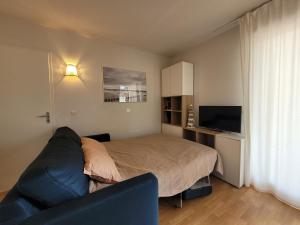 a bedroom with a bed and a couch and a television at Appartement 6 places proche plage et avec piscine in Le Verdon-sur-Mer