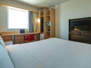 um quarto de hotel com uma cama, uma secretária e uma televisão em ibis Rio de Janeiro Barra da Tijuca no Rio de Janeiro