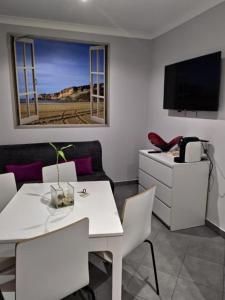 uma sala de estar com uma mesa branca e uma televisão em Casa do Terraço na Nazaré