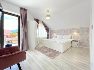 1 dormitorio con cama blanca y ventana grande en Vila Rolizo, en Brasov