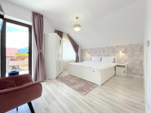 a bedroom with a white bed and a large window at Vila Rolizo in Braşov