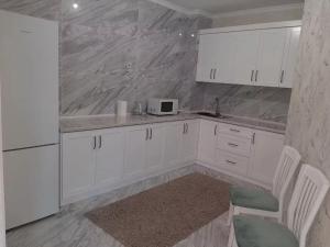 a white kitchen with white cabinets and a microwave at Ecohouse in Bishkek