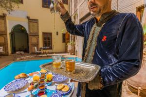 um homem segurando uma bandeja de comida e bebidas em Riad Il Parco dei Principi em Marrakech