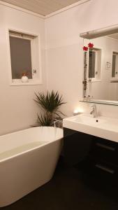 a white bathroom with a tub and a sink and a mirror at Villa with great view in Sandnes